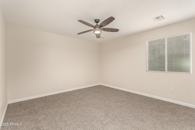 carpeted spare room featuring ceiling fan, visible vents, and baseboards