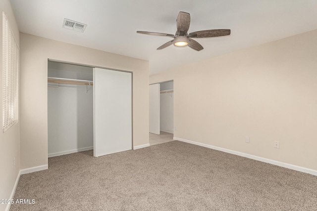 unfurnished bedroom featuring light carpet, a closet, visible vents, and baseboards