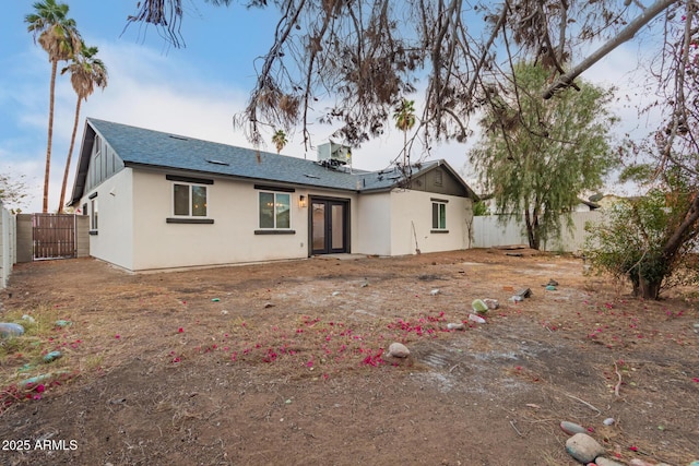 rear view of property featuring french doors, roof with shingles, and a fenced backyard