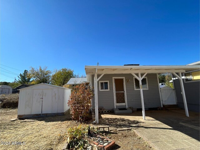 rear view of property with a carport and a storage unit