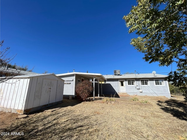 back of property with central AC unit and a shed