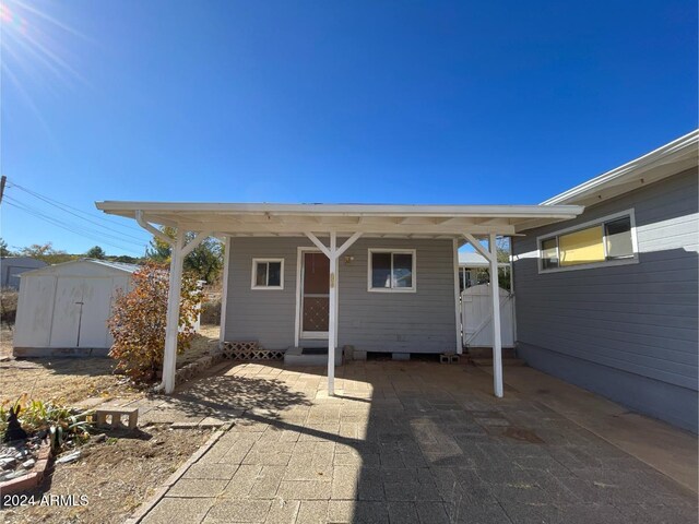 back of property with a shed, a carport, and a patio area