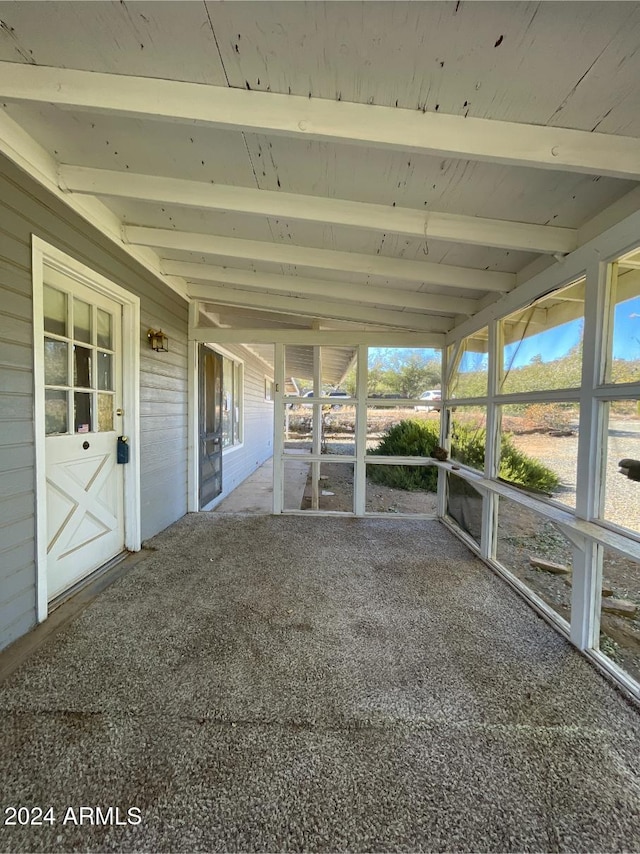 unfurnished sunroom featuring lofted ceiling with beams