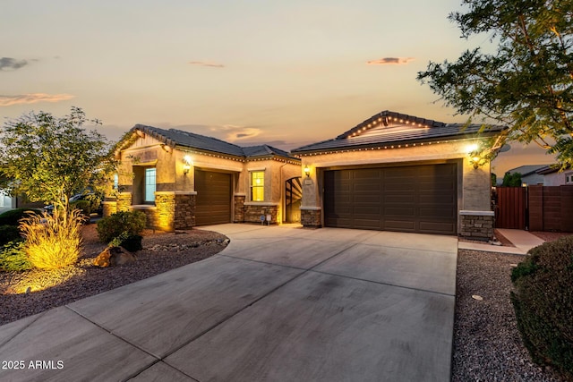 view of front of property featuring stone siding, concrete driveway, an attached garage, and roof mounted solar panels