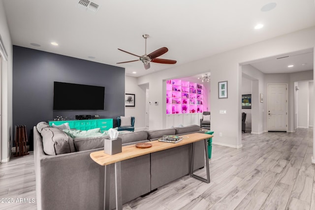 living area with recessed lighting, visible vents, light wood-style floors, a ceiling fan, and baseboards