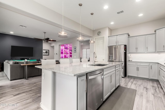 kitchen with light wood finished floors, visible vents, stainless steel appliances, and a sink