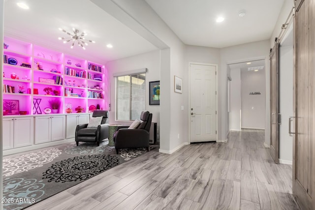 interior space featuring a barn door, baseboards, light wood-style floors, a chandelier, and recessed lighting