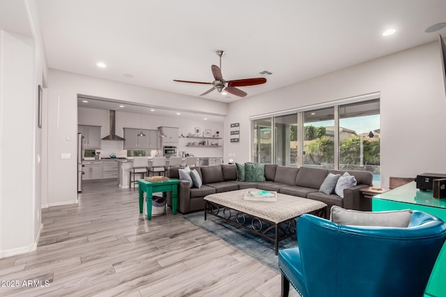 living room featuring baseboards, visible vents, a ceiling fan, light wood-type flooring, and recessed lighting