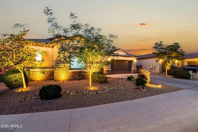 view of front of home with stone siding, concrete driveway, an attached garage, and stucco siding