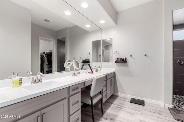 bathroom with double vanity, baseboards, visible vents, wood finished floors, and a sink