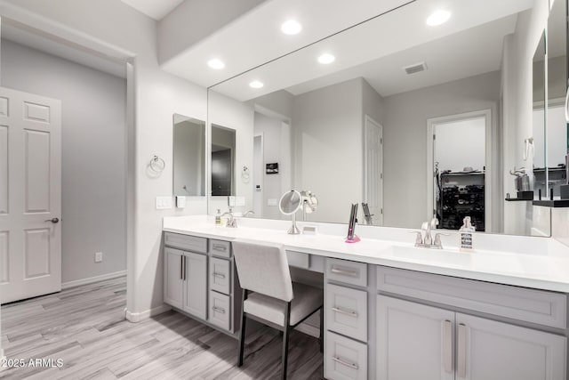 full bath with double vanity, recessed lighting, visible vents, a sink, and wood finished floors