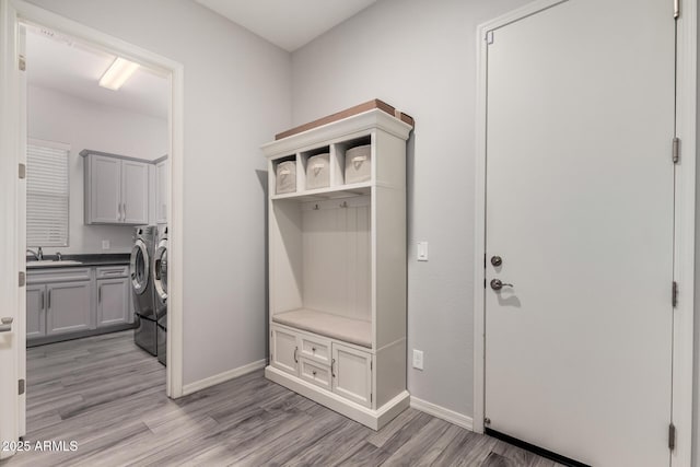 mudroom featuring light wood finished floors, baseboards, a sink, and washing machine and clothes dryer