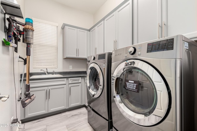 washroom with cabinet space, a sink, and independent washer and dryer