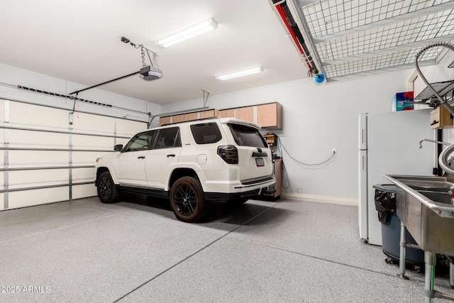 garage featuring baseboards, freestanding refrigerator, and a garage door opener