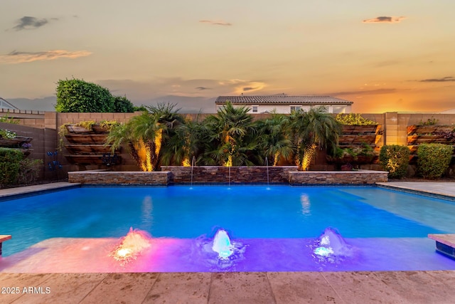 pool at dusk featuring a fenced backyard and a fenced in pool