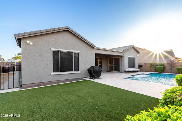 rear view of house with a patio, a fenced backyard, a lawn, a fenced in pool, and stucco siding