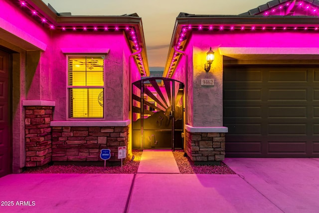 exterior space featuring stone siding, a gate, and stucco siding