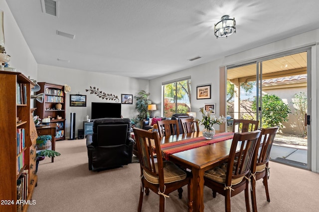 dining space with light colored carpet and a textured ceiling