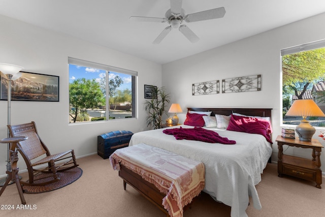 bedroom featuring ceiling fan, light colored carpet, and multiple windows