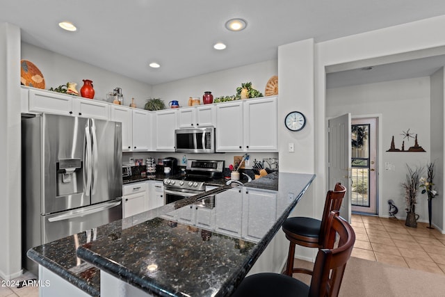 kitchen featuring kitchen peninsula, appliances with stainless steel finishes, white cabinetry, and a breakfast bar area