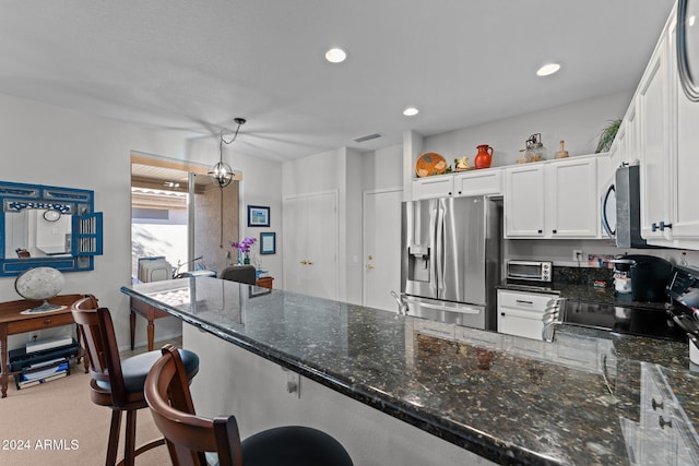 kitchen featuring white cabinetry, stainless steel appliances, kitchen peninsula, decorative light fixtures, and a breakfast bar area