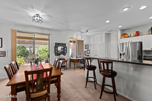 dining space with a chandelier, light colored carpet, and a textured ceiling