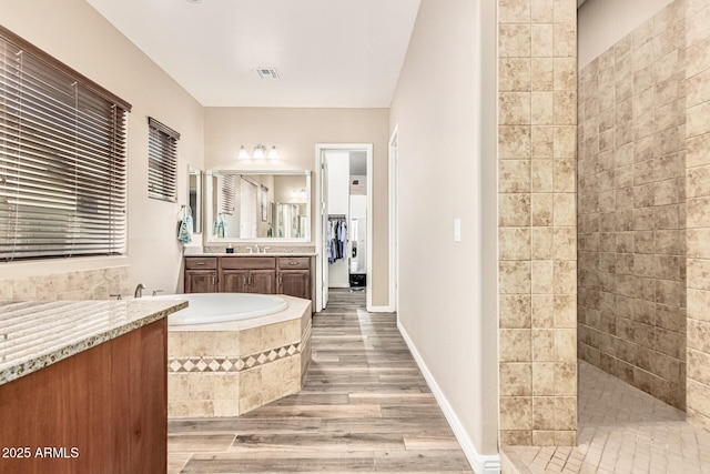 7242 W Rowel Rd, Peoria, AZ 85383 - bathroom featuring wood finished floors, vanity, a walk in shower, and a garden tub