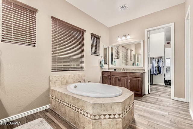 7242 W Rowel Rd, Peoria, AZ 85383 - bathroom featuring vanity, a garden tub, wood finished floors, and a spacious closet