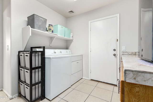 clothes washing area featuring washer and clothes dryer and light tile patterned floors