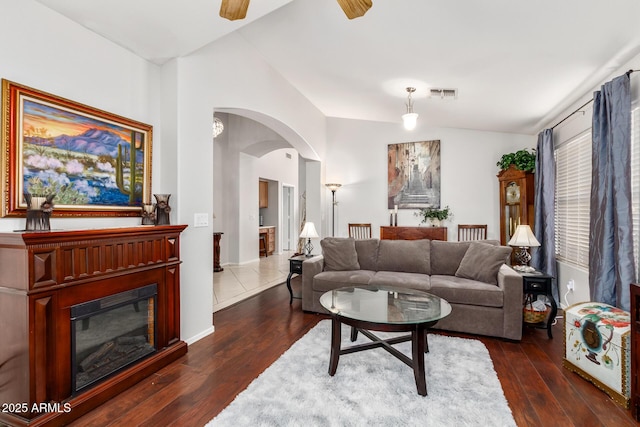 living room with ceiling fan, dark hardwood / wood-style flooring, and vaulted ceiling