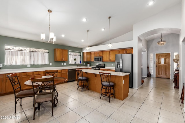 kitchen with decorative light fixtures, a breakfast bar area, a notable chandelier, a kitchen island, and stainless steel appliances