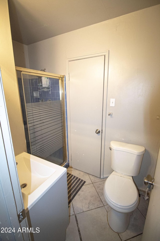 bathroom featuring tile patterned flooring, vanity, toilet, and a shower with door