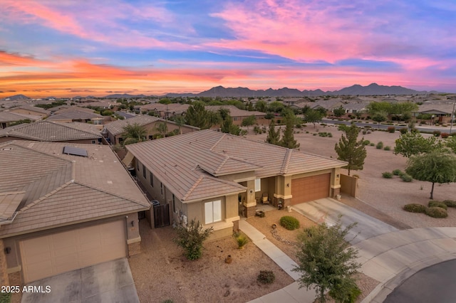view of front of property with a garage, driveway, a tile roof, stucco siding, and a mountain view