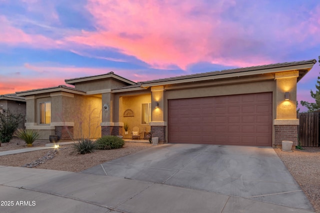 prairie-style house with brick siding, concrete driveway, and stucco siding