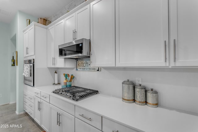 kitchen with appliances with stainless steel finishes, white cabinets, light countertops, and baseboards