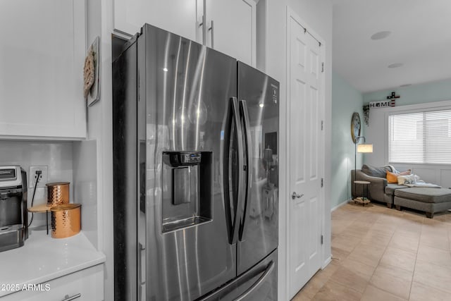 kitchen featuring stainless steel fridge with ice dispenser, white cabinets, light countertops, and open floor plan