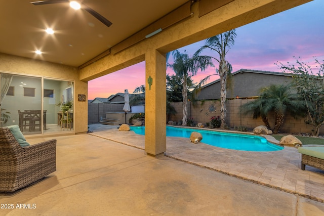 pool at dusk featuring a fenced backyard, a hot tub, a ceiling fan, and a patio