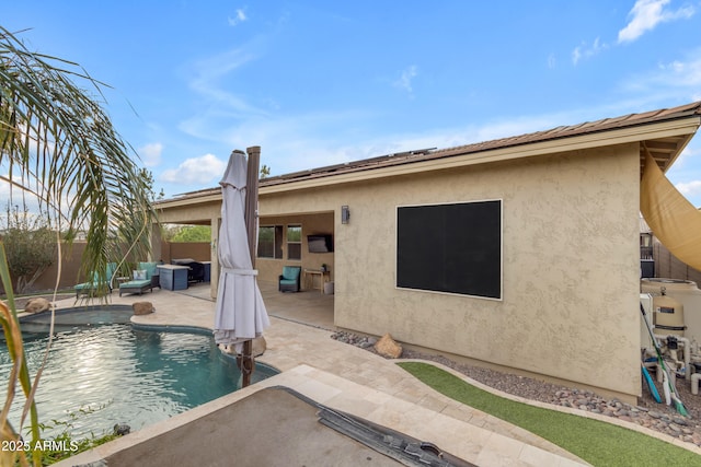 rear view of property with a patio area, fence, and stucco siding
