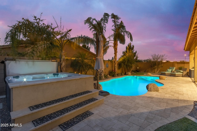 pool at dusk featuring a covered hot tub, a fenced backyard, and a patio