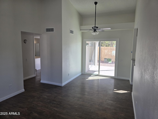 unfurnished room with a high ceiling, ceiling fan, and dark hardwood / wood-style flooring