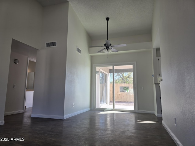 interior space featuring a towering ceiling, a textured ceiling, dark hardwood / wood-style floors, and ceiling fan