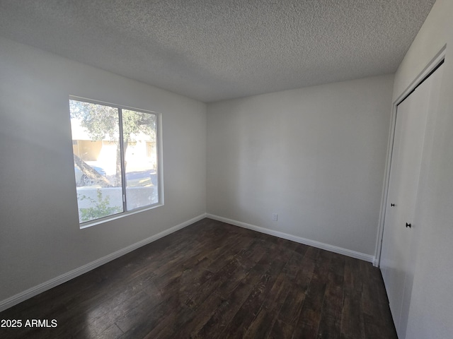 unfurnished bedroom featuring a textured ceiling, dark hardwood / wood-style flooring, and a closet