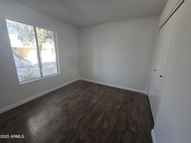 empty room with dark hardwood / wood-style floors and a textured ceiling