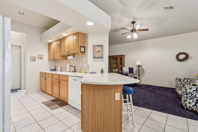 kitchen with light tile patterned floors, white appliances, backsplash, a kitchen bar, and kitchen peninsula