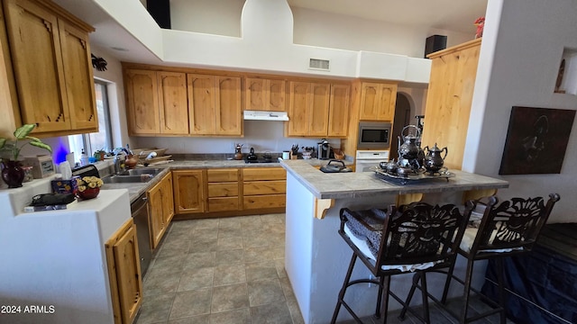 kitchen featuring tile countertops, a kitchen bar, sink, and appliances with stainless steel finishes