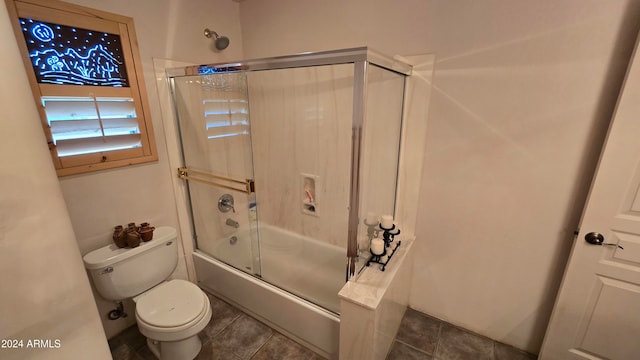 bathroom featuring toilet and combined bath / shower with glass door