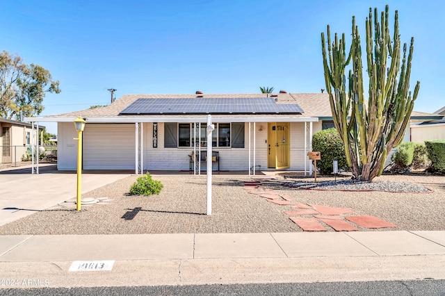 ranch-style house with solar panels, a porch, and a garage