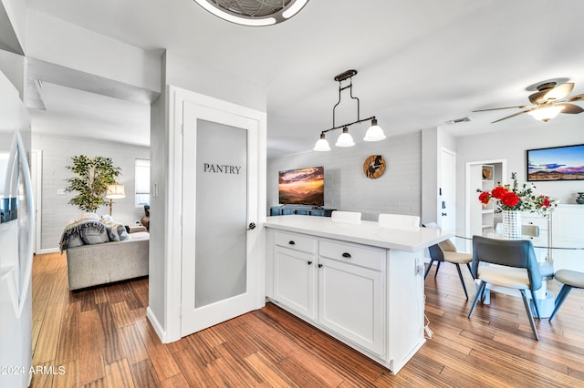 kitchen featuring white cabinetry, decorative light fixtures, brick wall, and light hardwood / wood-style flooring