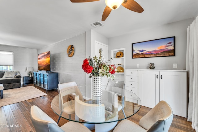 dining space featuring ceiling fan, brick wall, and dark hardwood / wood-style flooring