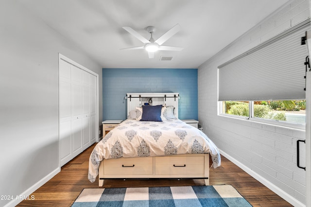 bedroom featuring brick wall, a closet, dark hardwood / wood-style flooring, and ceiling fan